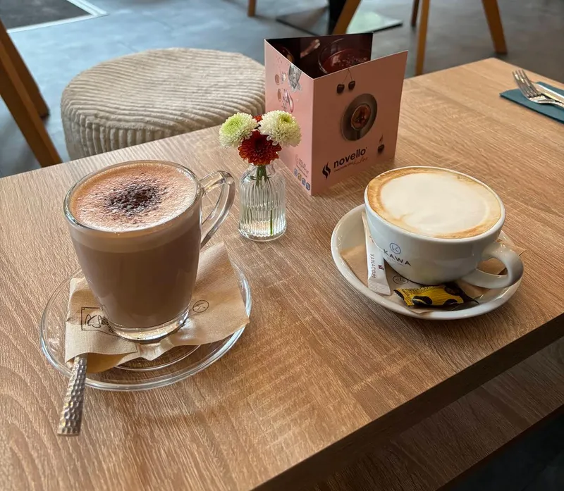 Heiße Schokolade und Cappuccino auf Holztisch mit Blumenvase