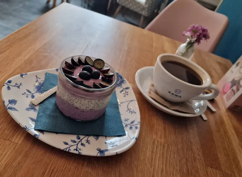 Chia-Pudding mit Beeren und Pflaumen neben schwarzem Kaffee
